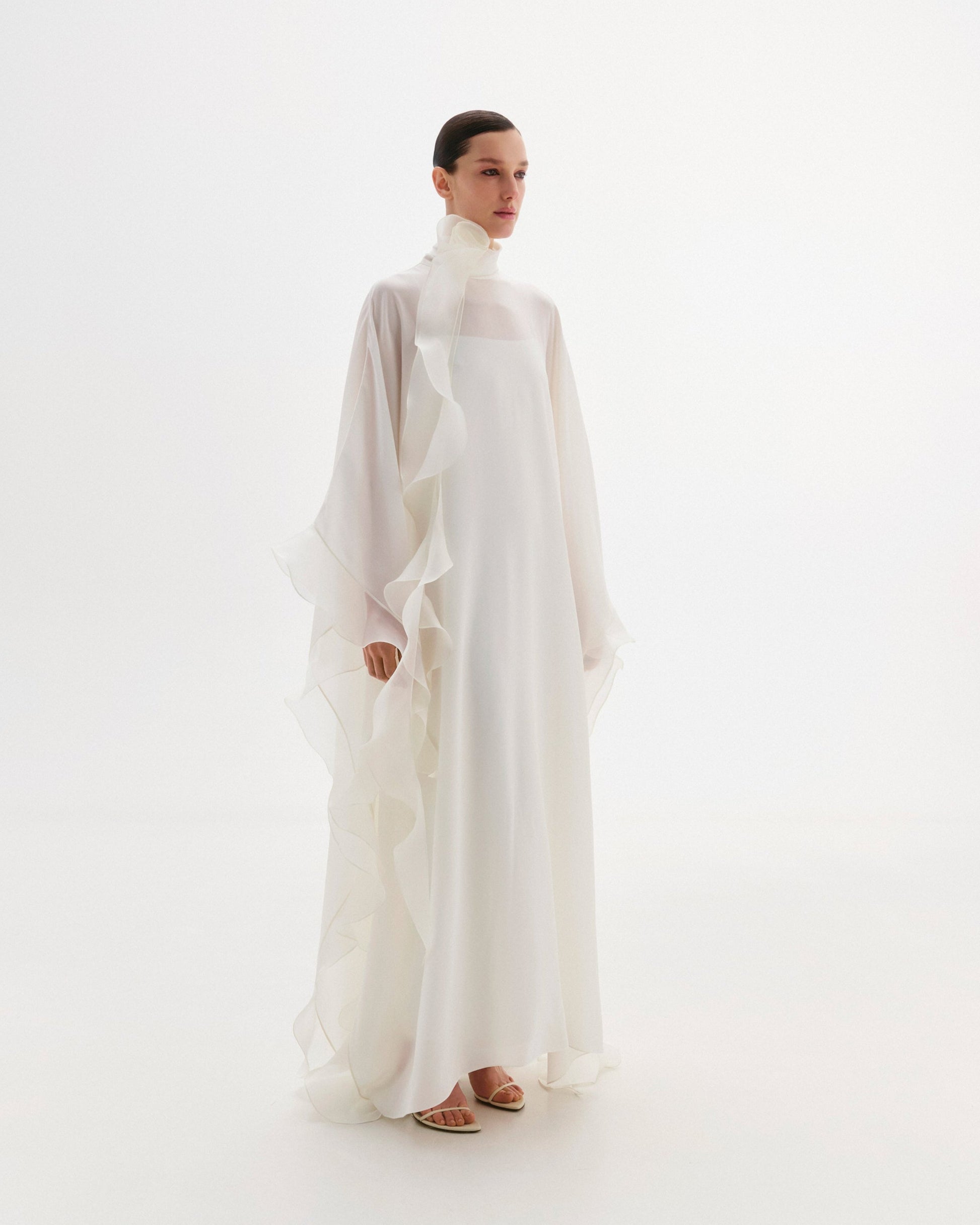 High-neck cape dress adorned with cascading decorative accents.