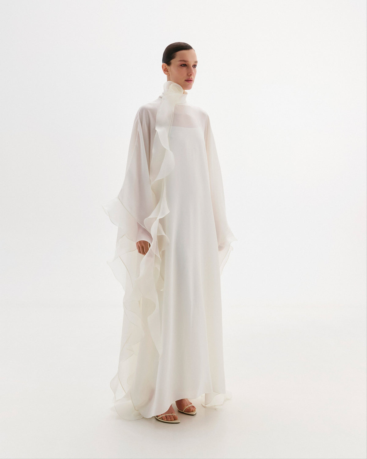 High-neck cape dress adorned with cascading decorative accents.